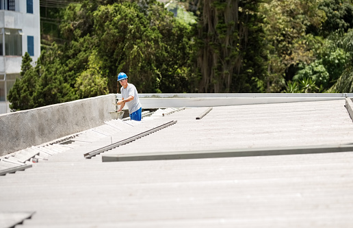 Shot of a mason worker wearing hardhat constructing a rooftop with concrete