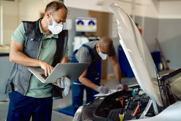 istock Auto mechanic using laptop while running engine diagnostic with his coworker in repair shop. 1277563983