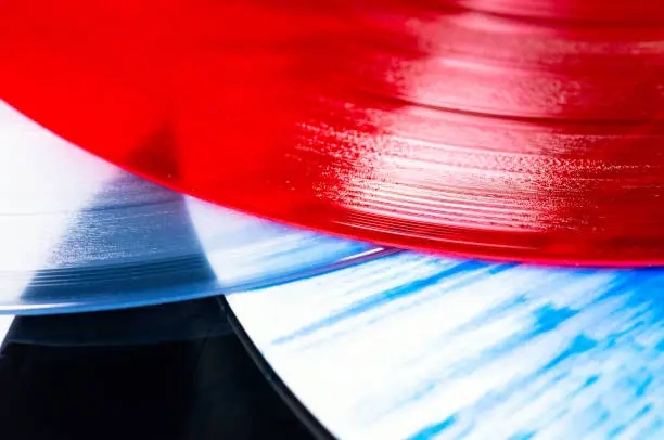 Close-up of a group of vinyl record editions, with a traditional black album, a patterned blue and white one, clear vinyl, and translucent red.