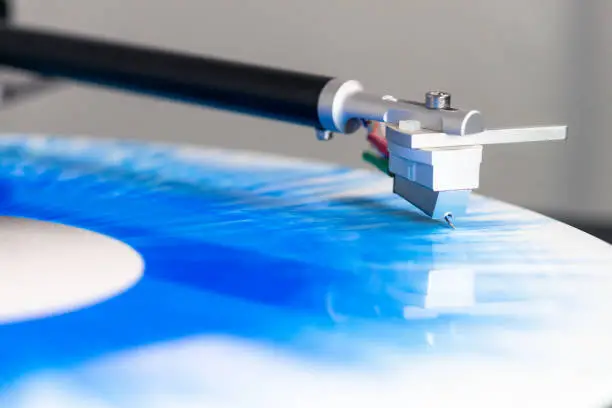 The tonearem of a modern record player reflected in the surface of a limited edition patterned vinyl.