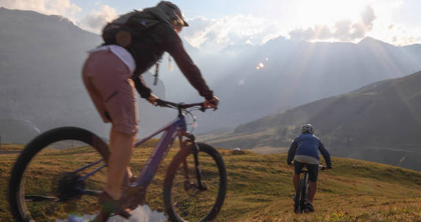 istock Mountain e-bikers ride through alpine meadow at sunrise 1277568183