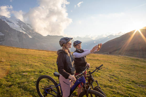 istock Female mountain e-bikers take selfies on cell phone sunrise 1277568621