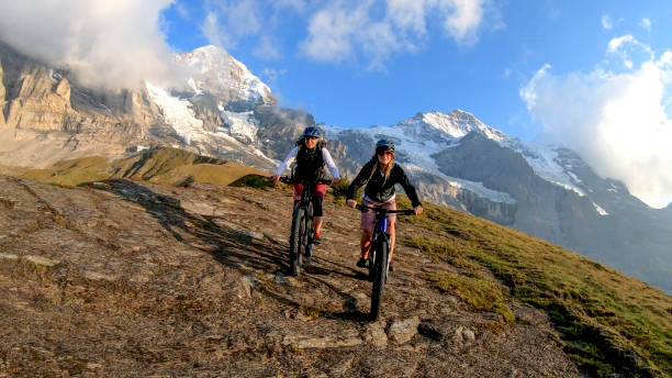 istock Female mountain e-bikers ride through alpine meadow at sunrise 1277568949