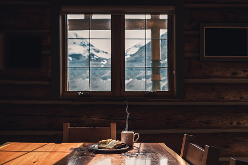 Sliced bread with hot coffee on wood table in wooden lodge at morning