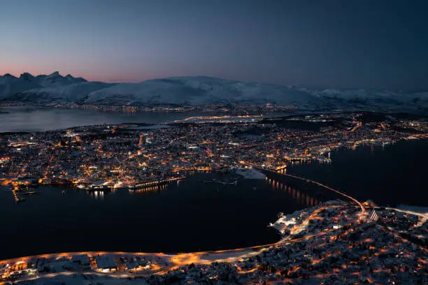 Tromsø Norway cityscape glowing at night. Bird's eye view aerial.