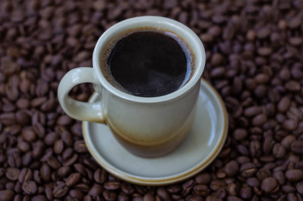 istock Black coffee in light brown cup on coffee beans background 1277574450