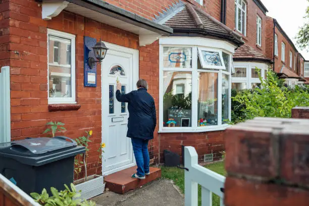 A mature woman knocks on her daughters front door to help her out taking her children to work in the morning.