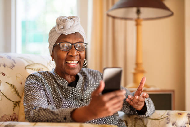 istock Smiling senior woman video calling on her phone while sitting at home 1277578338