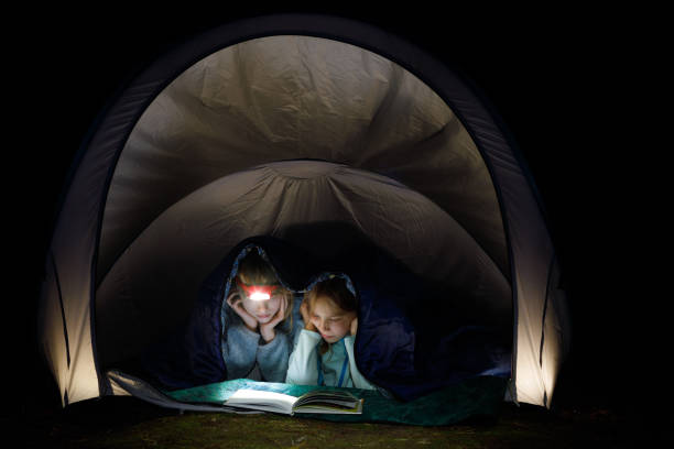 istock Girls reading a book with torch at night during summer holidays 1277579280