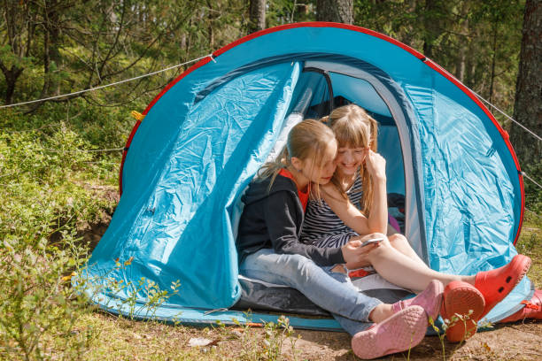 istock Girls using smartphone sitting in a camping tent during summer holidays 1277579360