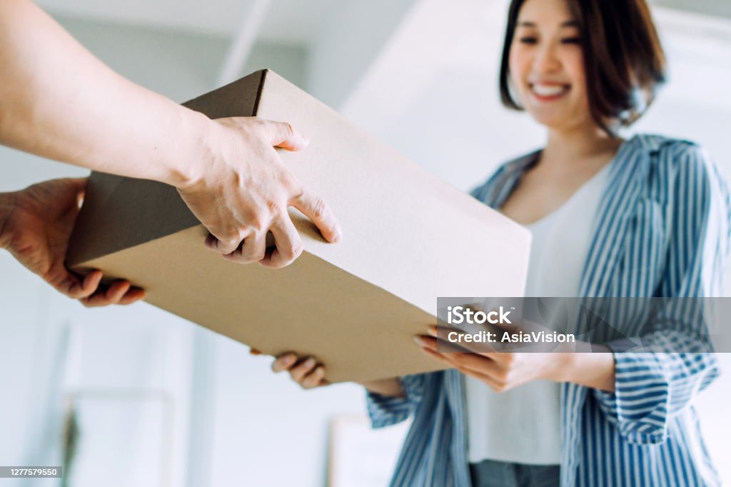 Close up of a courier person making a delivery to a customer at home. Providing a swift express delivery straight into customer's hands Delivering Stock Photo