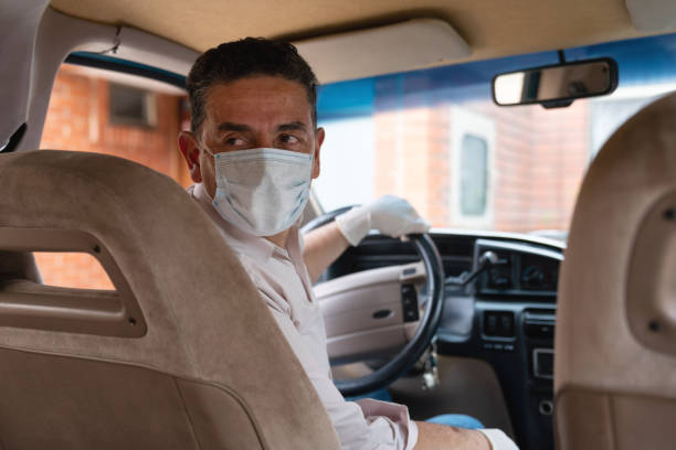 Driver wearing a facemask and gloves in his car Portrait of a Latin American driver wearing a facemask and gloves in his car during the COVID-19 pandemic car rental covid stock pictures, royalty-free photos & images