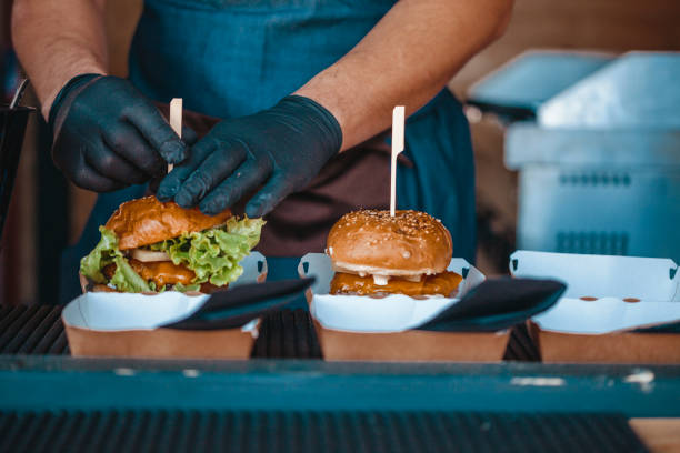 Die Hände des Küchenchefs bereiten die Burger zum Servieren vor – Foto