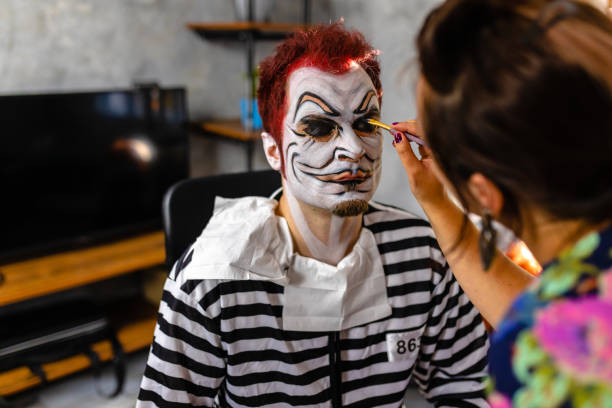 istock Stage makeup artist using precise brush strokes so the mask can be impressible for a Halloween party 1277586442