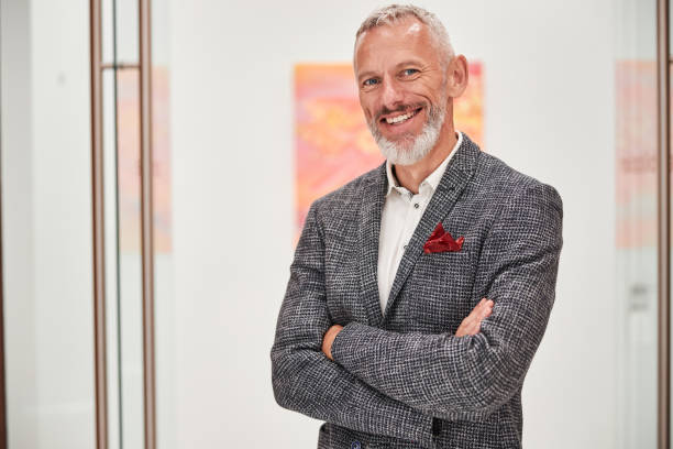 istock Smiley grey-haired man in a fancy blazer posing indoors 1277587723