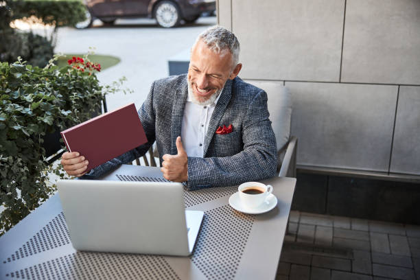 istock Happy senior man holding a red box during a videocall 1277587836