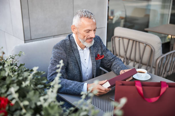 istock Aged man smiling and looking at a red gift box 1277587841