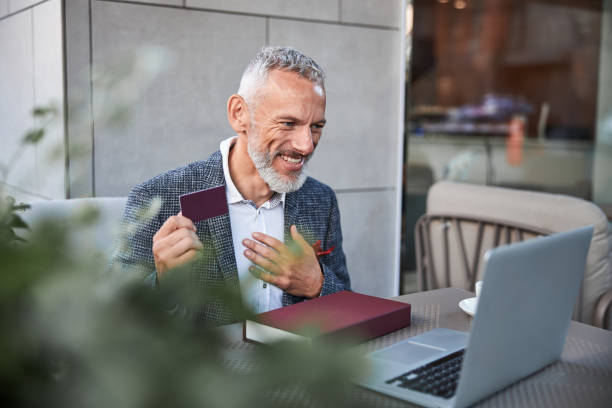 istock Joyous senior citizen showing a plastic card to a laptop webcam 1277587850