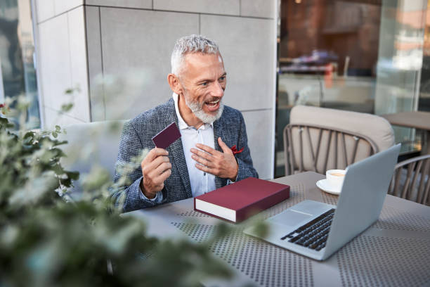 istock Grey-haired senior man smiling and showing a plastic card 1277587852