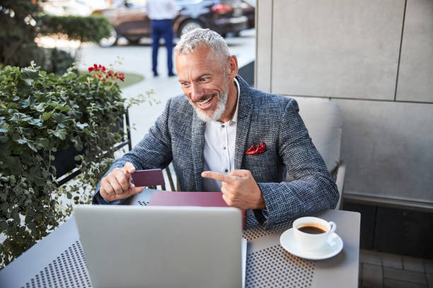 istock Energetic grey-haired man making a video-call and showing a card 1277587866