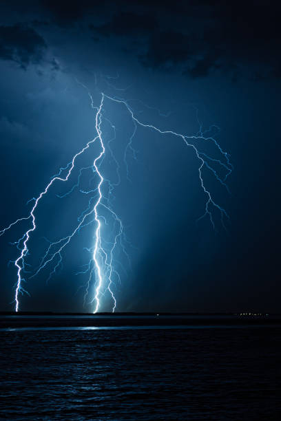 branched lightning bolts strike down in the water - summer landscape flash imagens e fotografias de stock