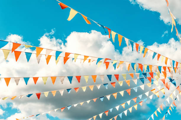 istock Colorful bright triangular Bunting flags on a blue sky background with white clouds. The concept of celebration and fun 1277590189