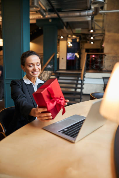istock Pleased brunette office worker demonstrating gift box 1277595428