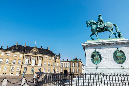 Copenhagen, Denmark - August 27, 2019: Equestrian statue of the King Frederick V and the facade of the Christian VIII Palace (Levetzau Palace) with people around in Amalienborg Square, Copenhagen, Denmark