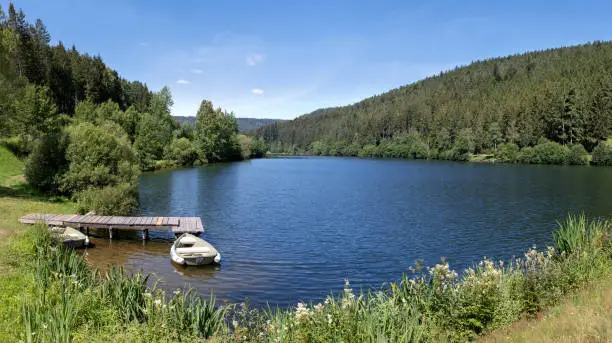 Idyllic lake with boat at the wooden jetty, taken at the dam Nagoldtalsperre in the Black Forest, Germany
