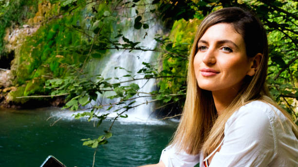 Young woman standing near a waterfall in forest