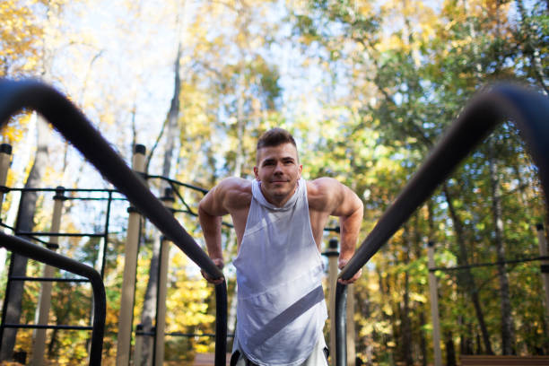 istock Fit man doing triceps dips on parallel bars at park exercising outdoors 1277607441