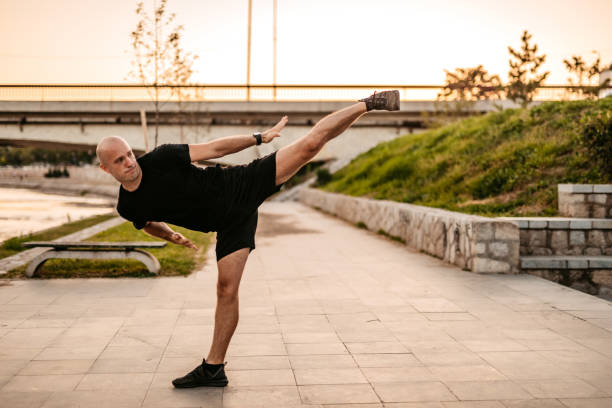 Young sporty man doing high kick outdoors