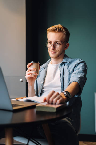 istock Caucasian man college student in glasses drinking coffee while studying 1277609313