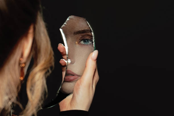 istock Young perfect woman holding broken self-image mirror on black background 1277611940