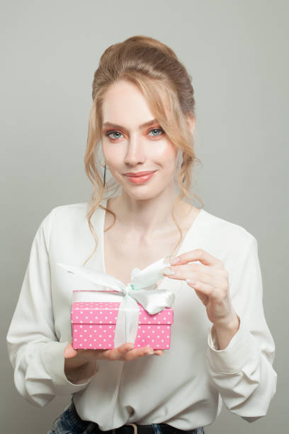 istock Nice woman holding pink gift on gray background 1277611958