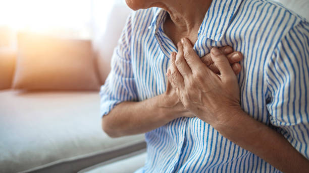 動揺は、心臓発作を持つ胸に触れる痛みの痛みを感じる成熟した中年女性を強調しました ストックフォト