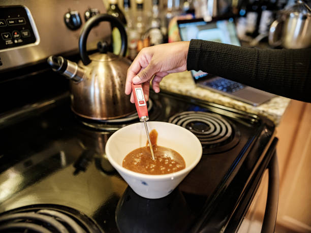 Close up of unrecognizable man and his wife cooking soup for lunch in the kitchen.