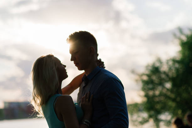 istock Couple in love back light silhouette at lake orange sunset 1277622055