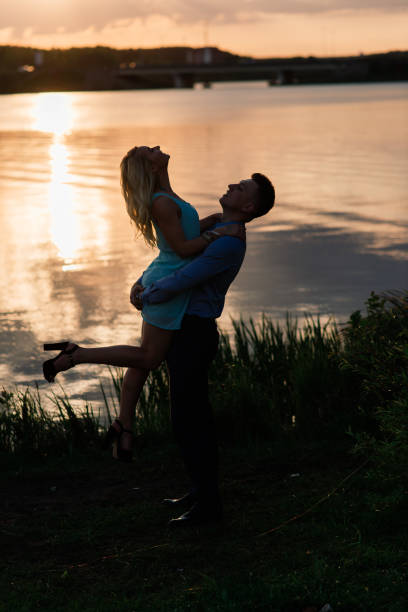 istock Couple in love back light silhouette at lake orange sunset 1277622066