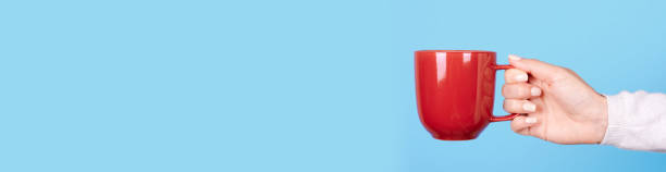 istock Hand with red mug with handle. Isolated on blue background, copy space template, banner. 1277622993