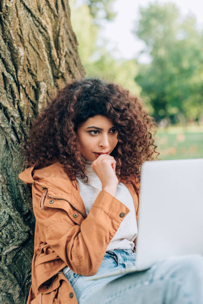 istock Selective focus of pensive freelancer looking at laptop in park 1277623302