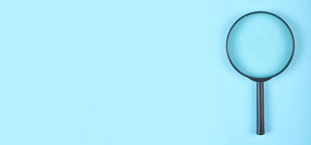 istock Black magnifying glass on blue background. Flat lay, overhead view image. 1277627916