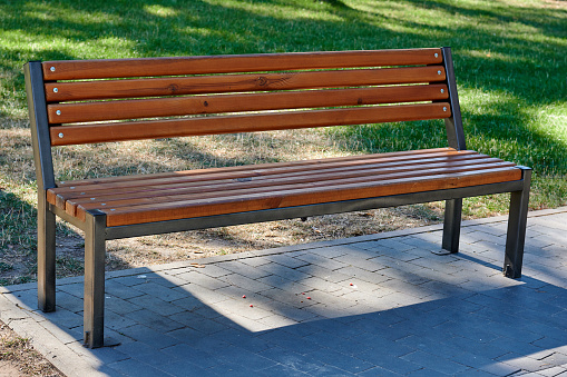 A wooden bench without people stands in a city park. High quality photo