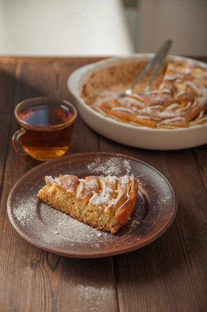 A piece of homemade pie on a plate of powdered sugar in a rustic style. Sliced apple pie with icing close-up and copy space.