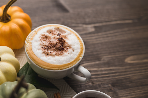 Pumpkins spice latte on a wooden and orange background with copy space