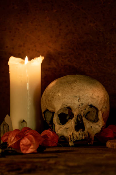 istock Human skull next to a white candle in a dark room 1277634803