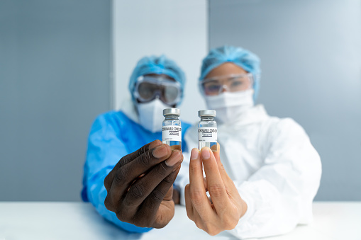 De cerca en la vacuna. Científicos multiétnicos en laboratorio de retención vial de la vacuna contra el coronavirus. photo