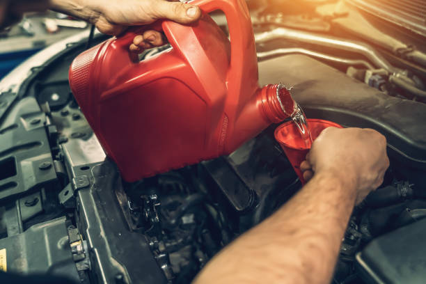 istock Worker hands pours flushing engine oil into engine to remove carbon deposits, correct timing change in car 1277638142