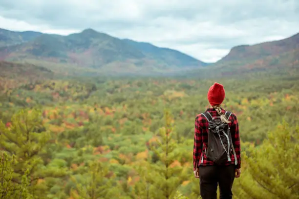 Female hiker in the mountains on a fall day with vibrant fall trees.