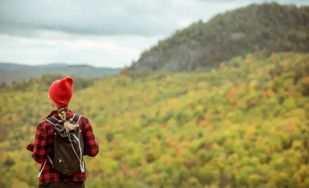 Female hiker in the mountains on a fall day with vibrant fall trees.